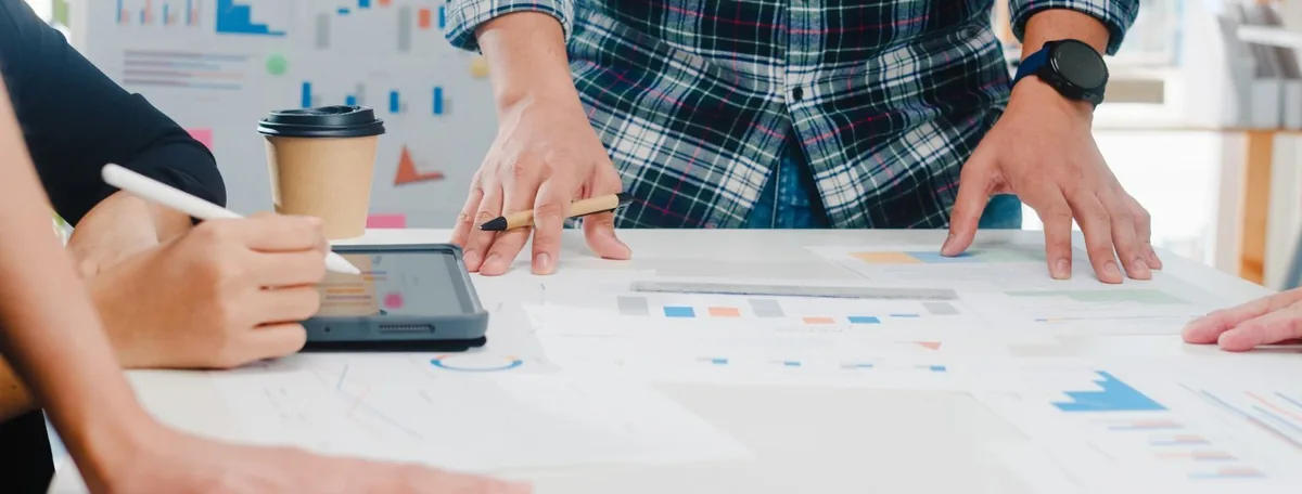 Twee collega&rsquo;s bespreken ontwerpen en grafieken aan een werktafel